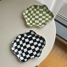 two black and white checkered plates sitting on a table next to a glass window