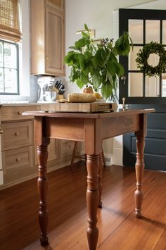 a wooden table sitting on top of a hard wood floor next to a potted plant