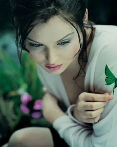 a woman in white shirt with green butterfly tattoo on her arm