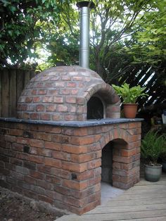 an outdoor brick pizza oven with potted plants