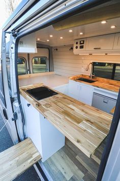 the interior of a camper van with wood counter tops and drawers on each side