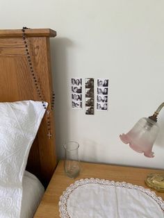 a bed with white linens and pictures on the wall next to a night stand