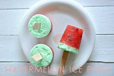 watermelon ice pops are on a white plate with a wooden stick in the middle