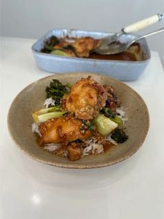 a plate with some food on it next to a bowl filled with rice and broccoli