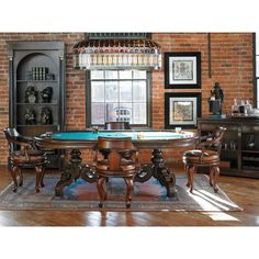 a dining room table with chairs and a pool table in front of a brick wall