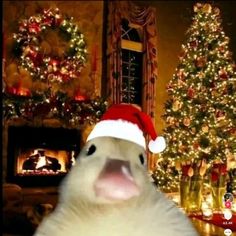 a white polar bear wearing a santa hat in front of a christmas tree and fireplace