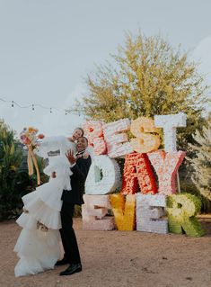 a bride and groom standing in front of large letters