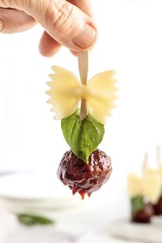 a person holding up a piece of food with leaves on it and chocolates in the background