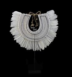 A large New Guinea white braided rope curved necklace with a fan of long Feather drops, and a collar of three overlapping rows of long pointed black sliced Shells. The biggest sliced Shells are 2.75 inches in length and the smallest are 2 inches in length. The inner diameter of the collar is, approximately 5 inches, and the maximum outer width of the necklace is, approximately 22.75 inches. The necklace has a maximum drop length of 18 inches, and is attached, at the top, by two groups of cream c Elegant White Woven Jewelry, White Elegant Woven Jewelry, White Bohemian Ceremonial Necklace, Feather Decor, Traditional Earrings, Braided Rope, New Guinea, Wedding Necklace, Hand Fan