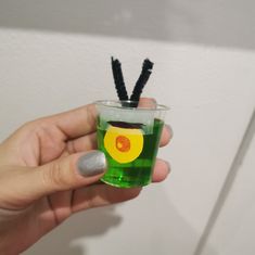 a person holding up a green drink with black straws