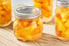 three jars filled with pickles on top of a wooden table