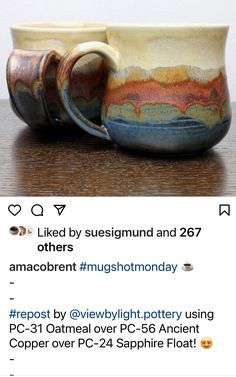 two coffee mugs sitting on top of a wooden table next to each other, one with