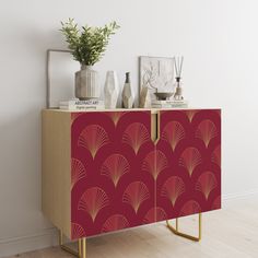 a sideboard with an art deco design on it and vases next to it