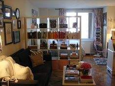 a living room filled with furniture and bookshelves next to a window covered in curtains