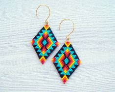 a pair of colorful beaded earrings sitting on top of a wooden table next to a white wall