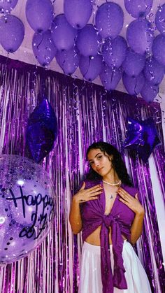 a woman standing in front of balloons and streamers with the words happy birthday on it