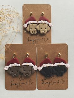 three dog earrings with santa hats on them