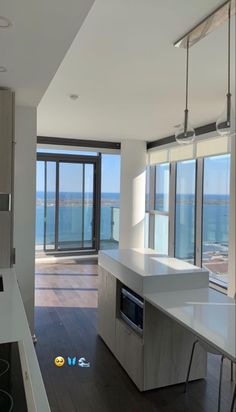 an empty kitchen with large windows overlooking the ocean