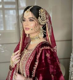 a woman wearing a red and gold bridal outfit