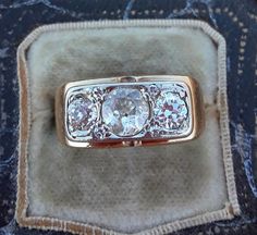 an antique ring with three old cut diamonds in it's center, sitting on a velvet case