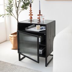 a black cabinet with candles and other items on it next to a white couch in a living room