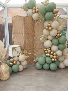 a balloon arch with gold and green balloons on the top, along with other decorations