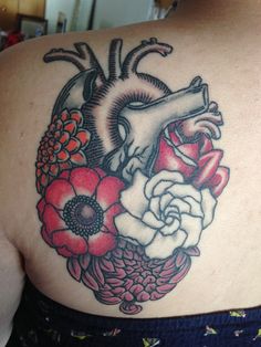 a woman's back with flowers and a heart tattoo on it