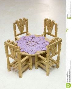 a wooden table with chairs and a crocheted doily on the table top