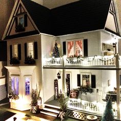 a doll house is lit up with christmas lights and decorations on the front porch area