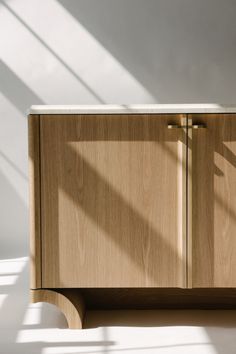 a wooden cabinet sitting on top of a white floor next to a light colored wall