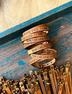 several leather bracelets with words on them are sitting next to each other in front of a blue wooden box