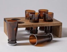 a wooden table topped with lots of glasses on top of a white floor covered in dirt