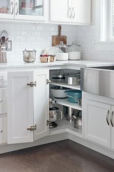 an open cabinet in a kitchen with pots and pans