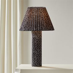 a lamp that is sitting on top of a table in front of a white curtain