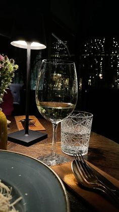 a glass of wine sitting on top of a wooden table next to a vase filled with flowers