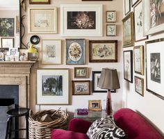 a living room filled with lots of framed pictures on the wall above a fire place