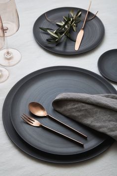 two black plates with gold forks and spoons