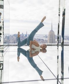 a man doing a handstand in front of a mirrored wall with cityscape