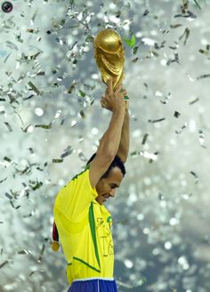 a man holding up a soccer ball in the air with confetti all around him