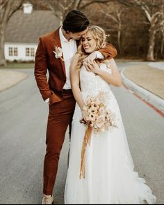 a bride and groom standing in the middle of an empty street with their arms around each other