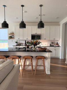 a kitchen island with stools in front of it next to a living room and dining area