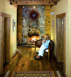 a woman sitting on a bench in front of a fire place inside of a house