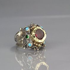 A magenta cubic zirconia ring made for a queen!It is ornate but delicate, statement piece but not oversize.The band is adjustable to any finger size and made of sterling silver set with natural turquoise gemstone and green cubic zirconia. The center is a bezel set faceted cubic zirconia and 9K solid gold, welded on sterling silver, which is hammered.You will feel like royalty when wearing it!Measurements: Center stone - 10mm Size:This queen ring is adjustable to any size, it has a small open so Unique Jeweled Anniversary Ring, Luxury Jeweled Rings As Gift, Luxury Jeweled Rings For Gift, Hammered Metal Jewelry, Silver Gold Ring, Queen Rings, Antique Style Rings, Accesories Jewelry, Aesthetic Jewelry