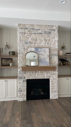 a living room with a fire place and shelves on either side of the fireplace that has a mirror above it