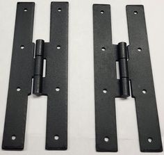 two black iron door hinges on a white surface