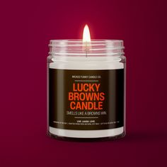 a candle that is sitting in front of a red background with the words lucky brown's candle on it