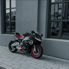 a red and black motorcycle parked in front of a building