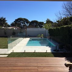 an empty swimming pool in the middle of a backyard with wooden decking and fence around it