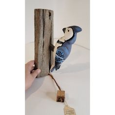 a blue bird perched on top of a piece of wood next to a wooden post