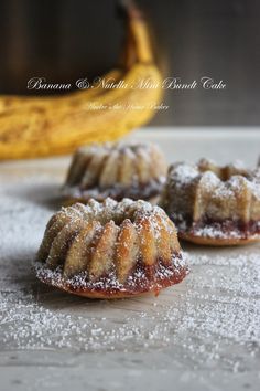 two pastries covered in powdered sugar sit on a table next to a banana